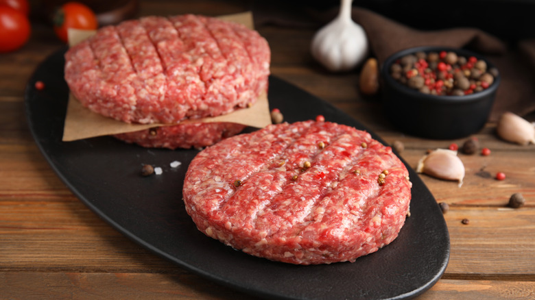 fresh burger patties displayed on counter with spices