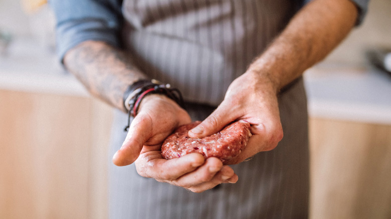 person shaping burger patties by hand