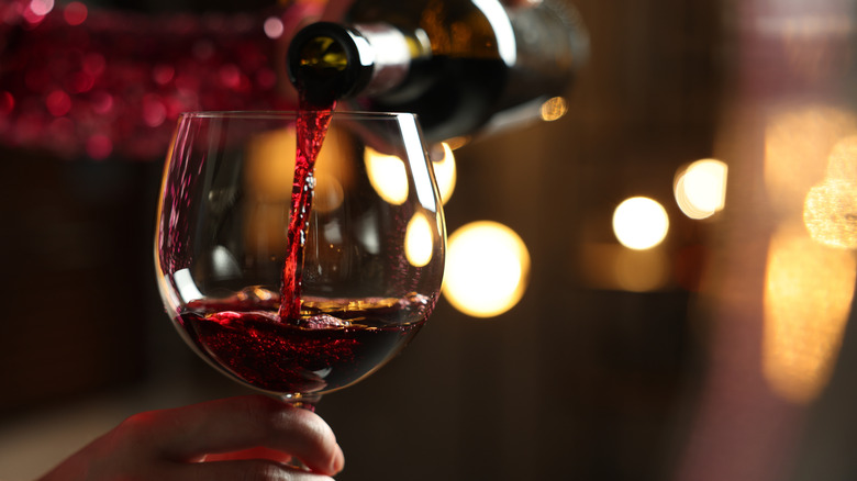 Red wine being poured from a bottle into a wine glass