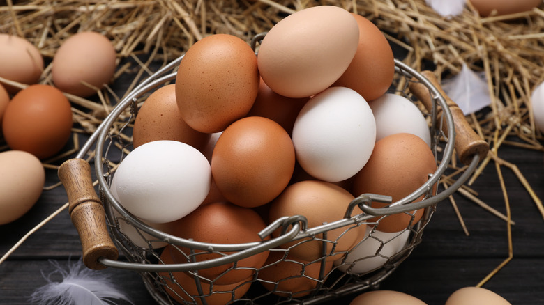 fresh farm eggs in a metal basket, surrounded by straw