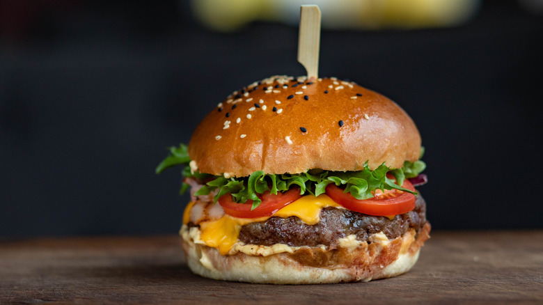 A cheeseburger on a wooden board.