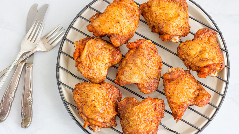 Fried chicken thighs on a wire rack in oven tray