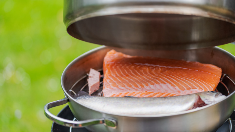 Salmon smoking in pot with lid open