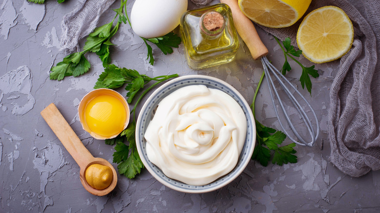 A bowl of mayo with oil, eggs, and lemons