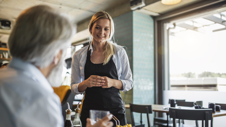 A server listens to a patron inside a restaurant