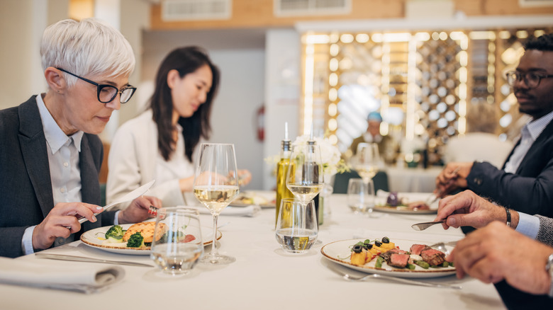 A diverse group of people dine inside a fine restaurant