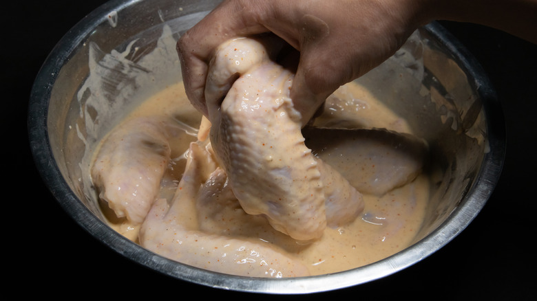 hand dipping wings in a marinade