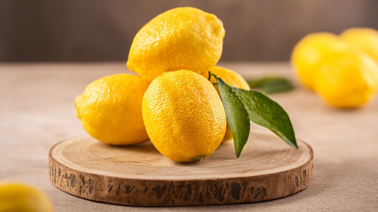 three lemons stacked on cutting board