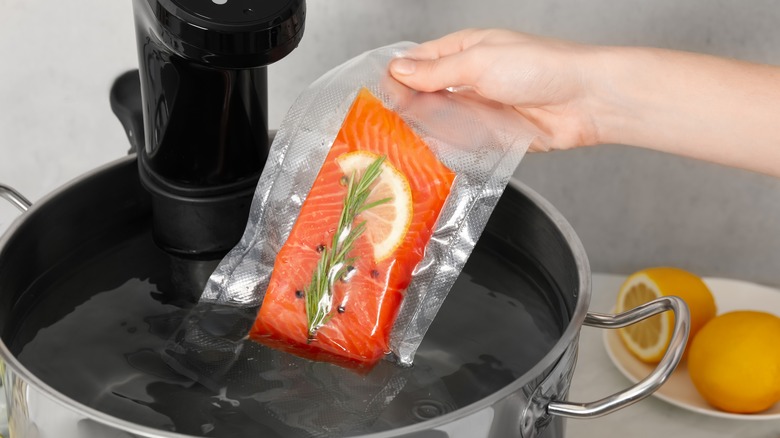 A woman putting a vacuum packed salmon filet into a sous vide setup