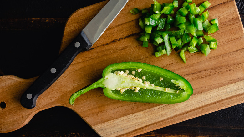 Chopped jalapeño on a cutting board with a knife