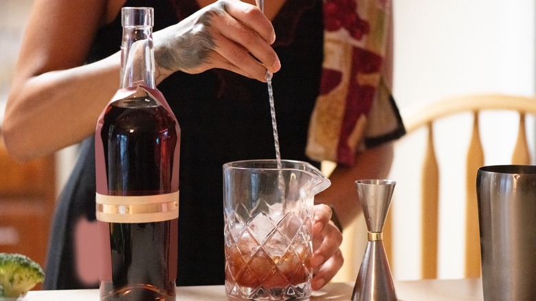 hand stirring cocktail with ice