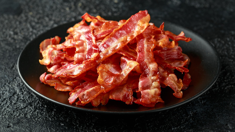 Cooked strips of bacon piled on a black plate