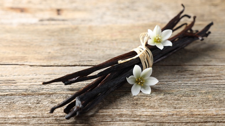 A bunch of vanilla beans wrapped in white string with a flower on the side