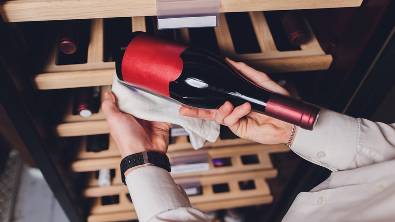 Someone selecting a wine from a rack