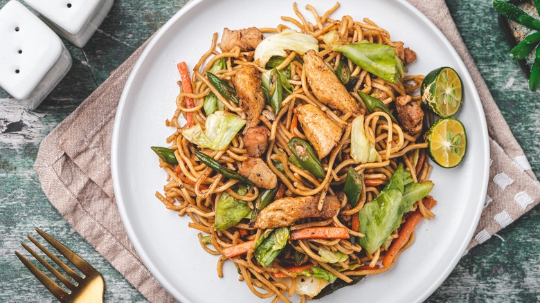 A plate of lo mein with chicken and veggies