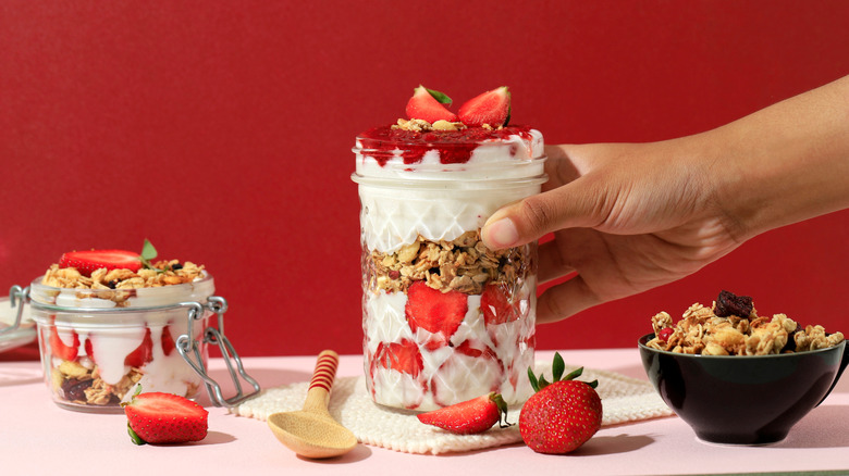 Yogurt parfaits are shown with strawberries, preserves, nuts, and granola.