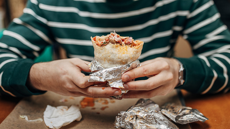 Man holding unwrapped burrito