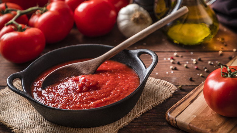 Tomato sauce in skillet with fresh tomatoes