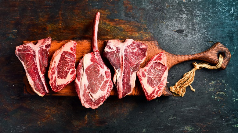 A variety of steaks on a wooden board