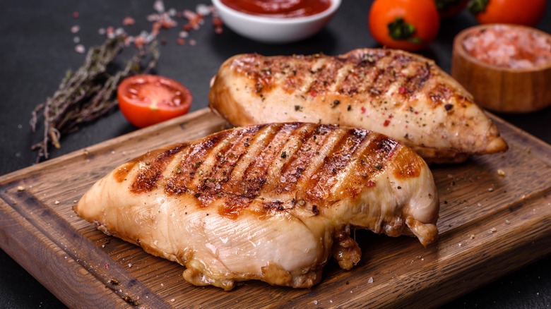 Cooked grilled chicken breasts on wooden cutting board