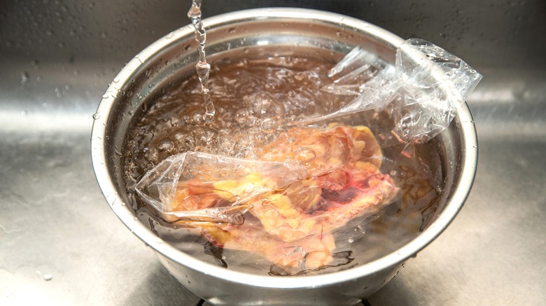 Meat defrosting in bowl of water