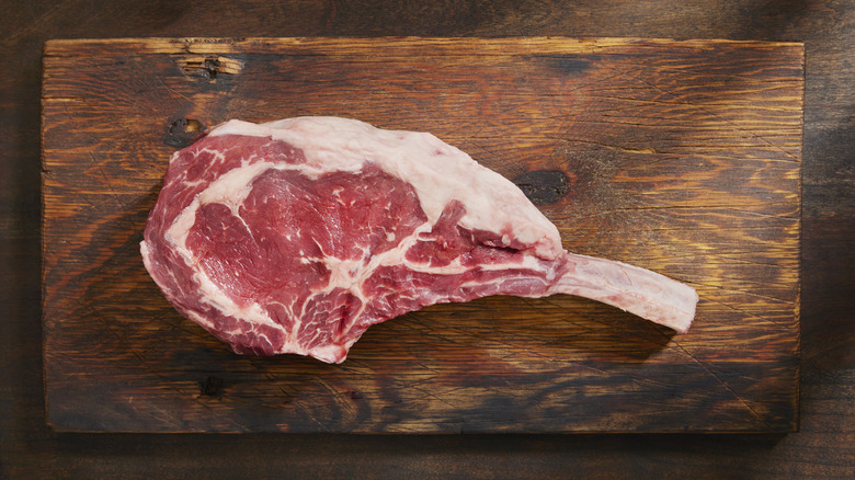 Raw steak on wooden cutting board