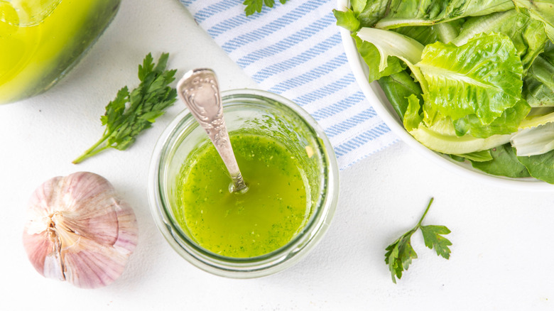 Infused herb oil next to a head of garlic