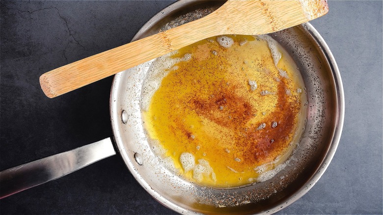 Browning butter in stainless steel pan with wooden spatula