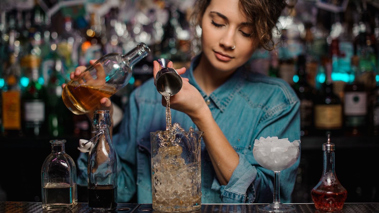 Bartender pouring alcohol into jigger for precise measurement