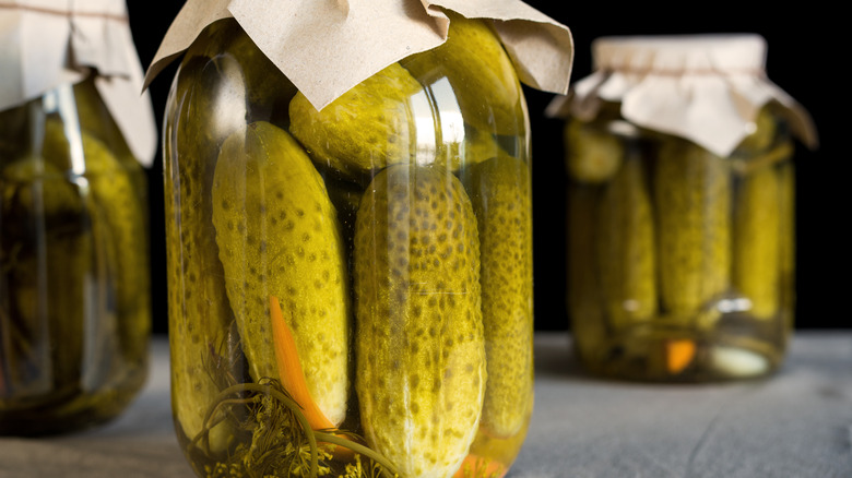 Three glass jars filled with dill pickles.