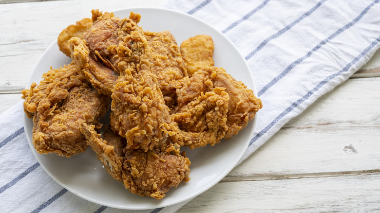 A plate of fried chicken on a table with a striped napkin.