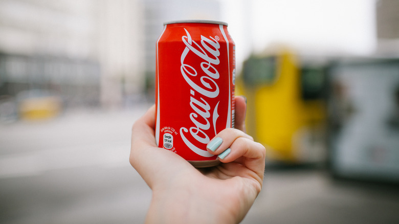 Hand holding can of Coca-Cola outside