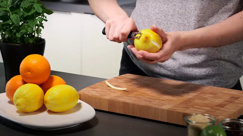 person using channel knife on lemon