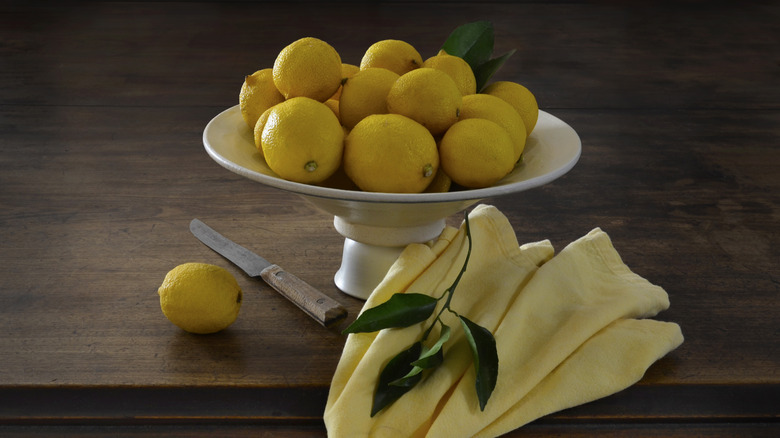 Bowl of lemons with knife on table