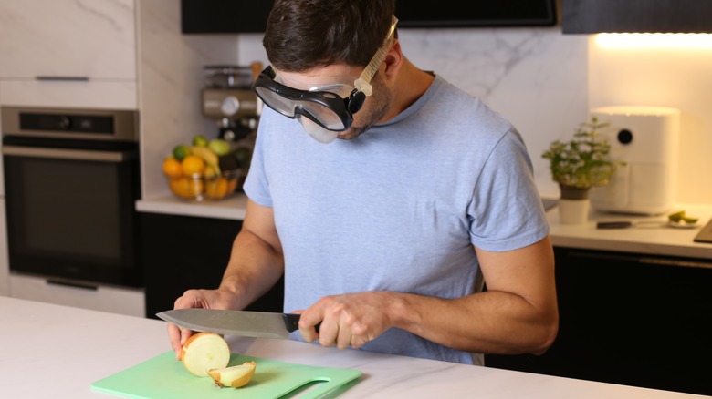 Man wearing a swim mask and chopping onions