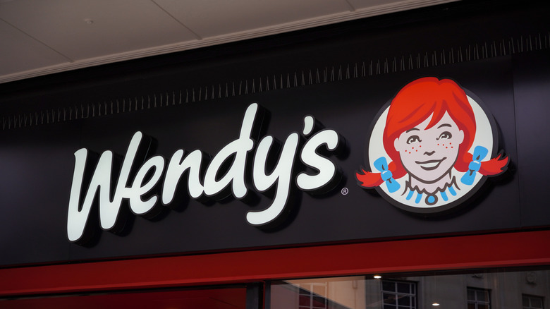 Large black sign with Wendy's written in white and the Wendy's logo next to it