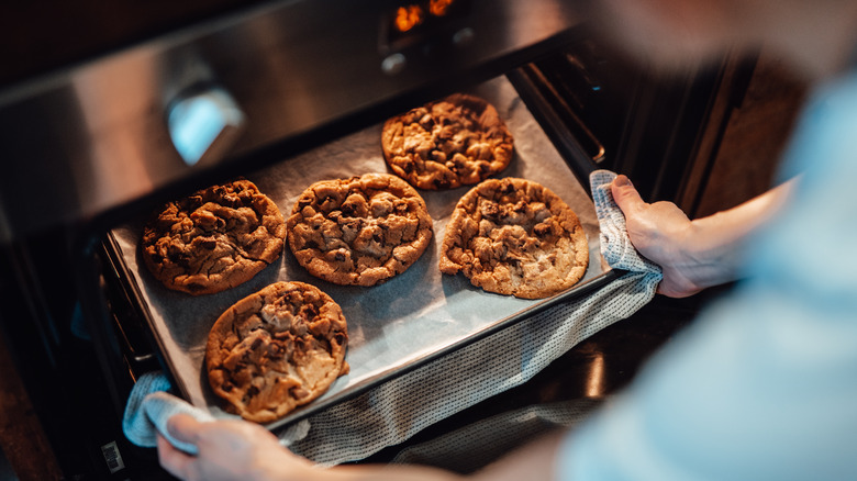 Person removing a tray of cookies from an oven