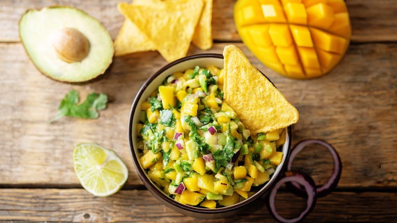 Bowl of mango guacamole, lime, and tortilla chips