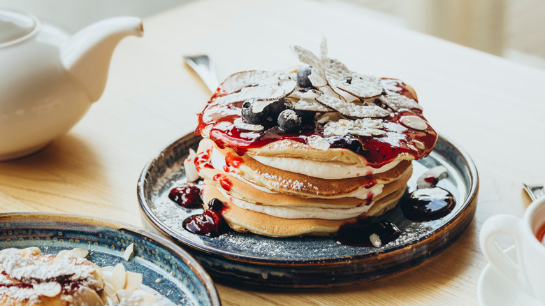 stack of pancakes with berries, almonds, and syrup