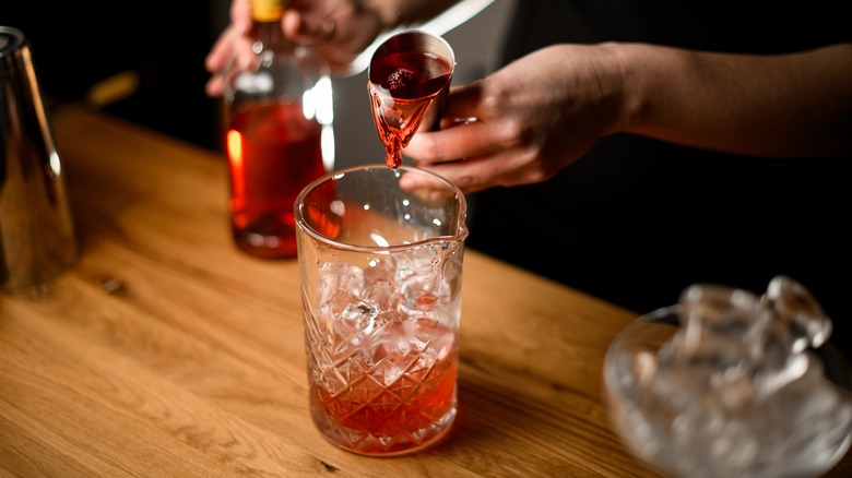 person making cocktail in glass