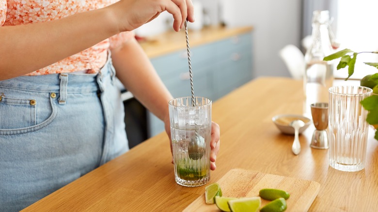 Person stirring cocktail at home