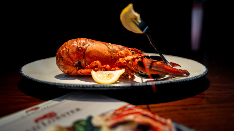 Whole cooked lobster on plate next to Red Lobster menu on table