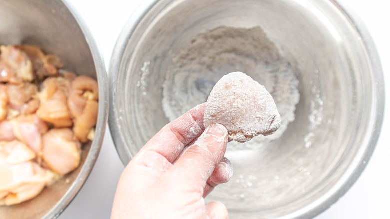 Dredging chicken pieces in flour