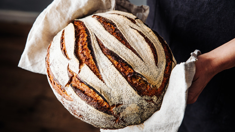 woman holding loaf of fresh bread