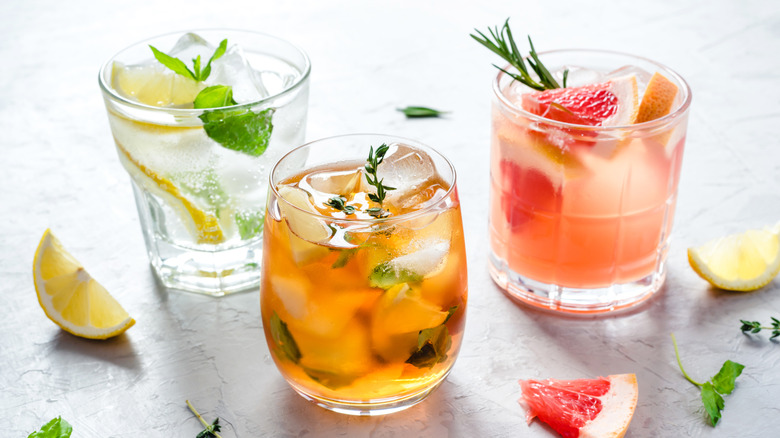 Three spritzes with citrus and herb garnishes