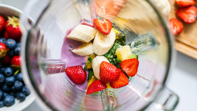 Overhead view of fresh fruit and yogurt in a blender