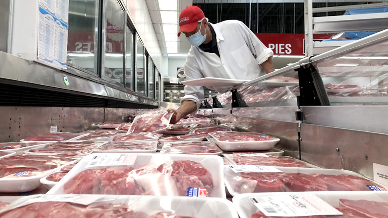 Costco employee places meat in aisle