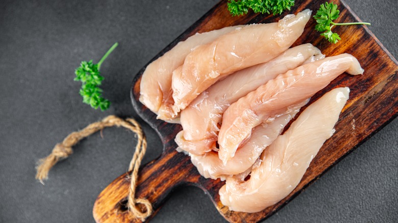 chicken tenderloins on wooden board