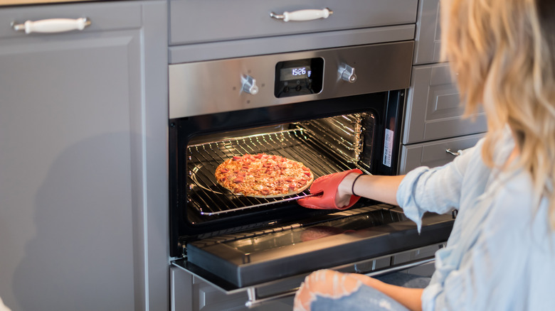 women removing pizza from oven