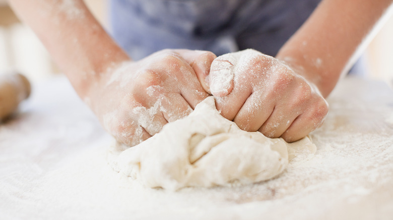 A pair of hands kneading dough